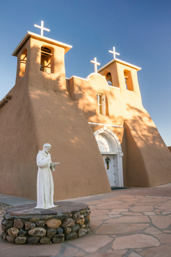 The first rays of sunlight on the bell towers of historic San Francisco de Assisi church in Taos, New Mexico. This Spanish mission was made famous in photographs by photographer.