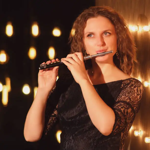 Photo of The female flautist, an accomplished musician, lit up the stage with her flute playing skills under the concert lights.