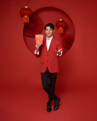 Happy Chinese new year. Asian man holding angpao or red packet monetary gift with text means great luck, great profit isolated on red background.