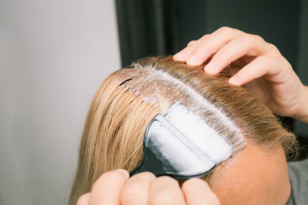 home made hair dye at home. woman dyeing her hair in front of mirror. - matéria corante imagens e fotografias de stock