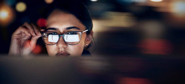 istock Woman, glasses reflection and computer at night for planning, website search and technology. Face of female working late on desktop, dark office and reading online network, focus vision and internet 1784017025