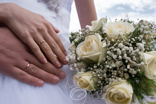 Wedding bouquet and hand showing wedding ring.