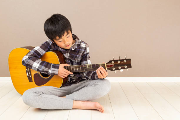 un garçon jouant de la guitare. - 12 13 years 13 14 years learning education photos et images de collection