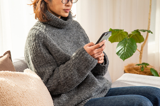 A woman using a smartphone in the living room.