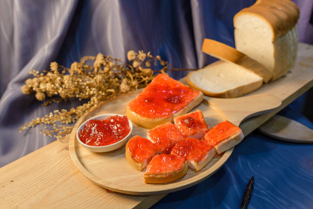 Slices of bread with strawberry jam on a wooden board.