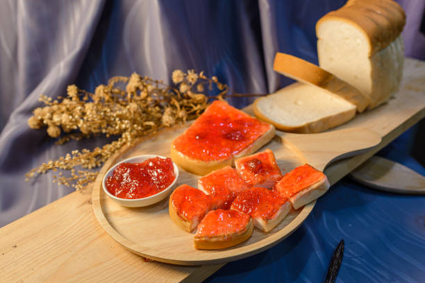 Slices of bread with strawberry jam on a wooden board.
