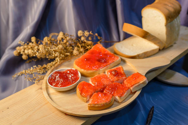 Slices of bread with strawberry jam on a wooden board.