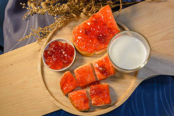 Slices of bread with strawberry jam on a wooden board.