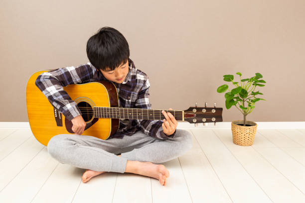 un garçon jouant de la guitare. - 12 13 years 13 14 years learning education photos et images de collection