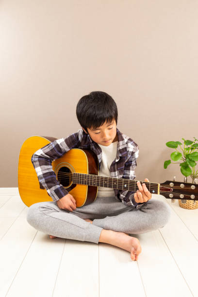 un garçon jouant de la guitare. - 12 13 years 13 14 years learning education photos et images de collection