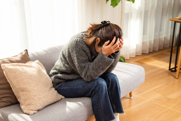 A woman holding her head in the living room. A woman holding her head in the living room. head in hands stock pictures, royalty-free photos & images
