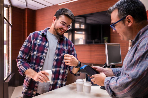Customer makes a payment with a smart watch at a small retailer stock photo