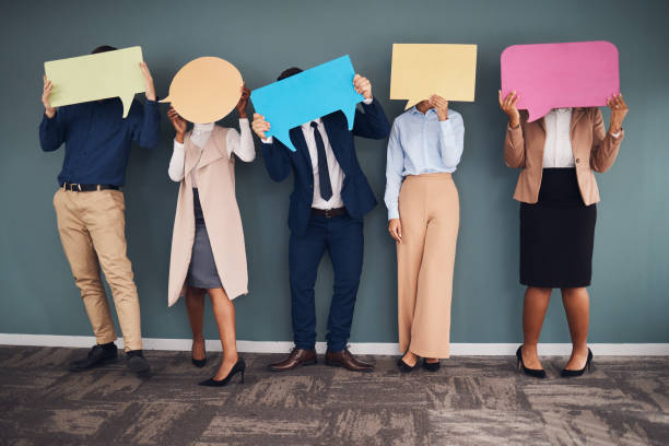 istock Business people, speech bubbles and communication in workplace, logo and feedback against grey wall. Group, staff and teamwork for advertise campaign, opinion and announcement with banner or creative 1784076277