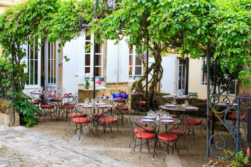 Open restaurant terrace under a grape vine in Saint-Emilion town, Gironde, France