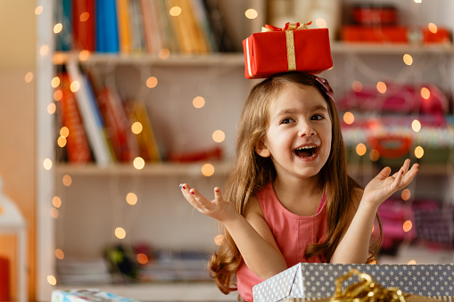 Cheerful girl oppening Christmas presents in her living room
