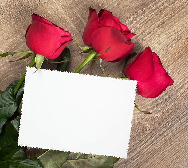 istock three red roses and blank sheet on wood 178407817