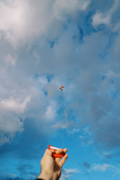 istock Man holds in his hand a spool of colorful kite string soaring in the sky 1784084341