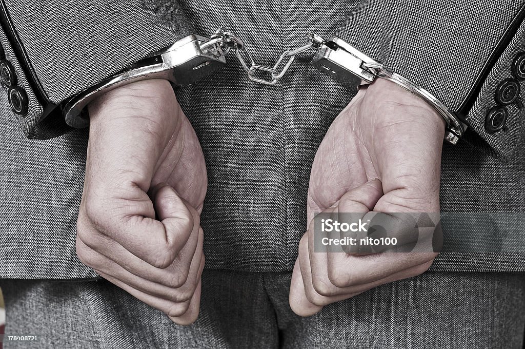 handcuffed man a man wearing a suit, with handcuffs in his wrists Adult Stock Photo