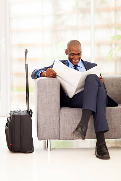 african businessman reading newspaper in airport african businessman reading newspaper in airport vip lounge newspaper airport reading business person stock pictures, royalty-free photos & images