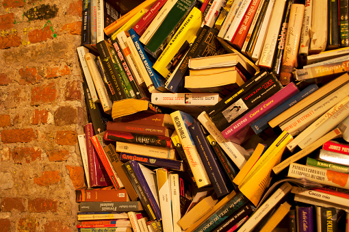 Detail of books Stacked Together in Disarray on a Brick Wall. Home Decore in Milano, Italy