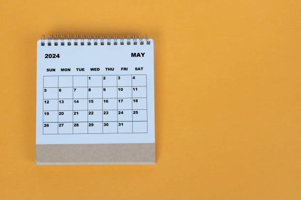 istock May 2024 desk calendar on yellow background. Directly above. Flat lay. 1784095581