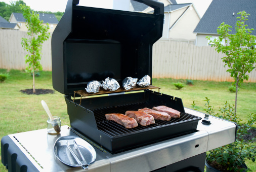 gas grill with open lid and rib eye steaks