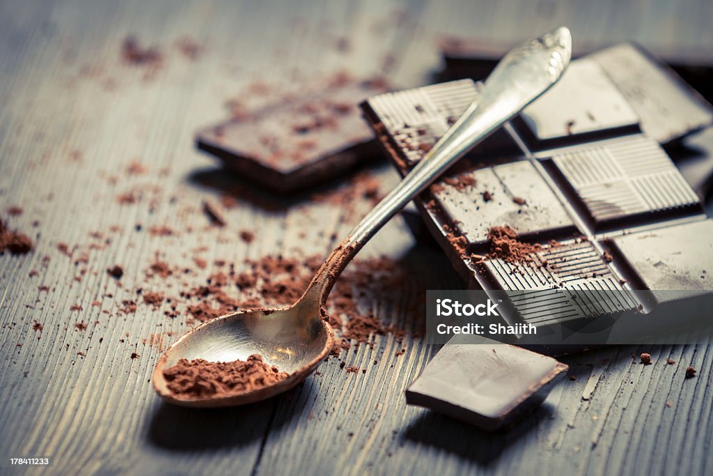 Poudre de cacao sur la cuillère et fond chocolat foncé - Photo de Tablette de chocolat libre de droits