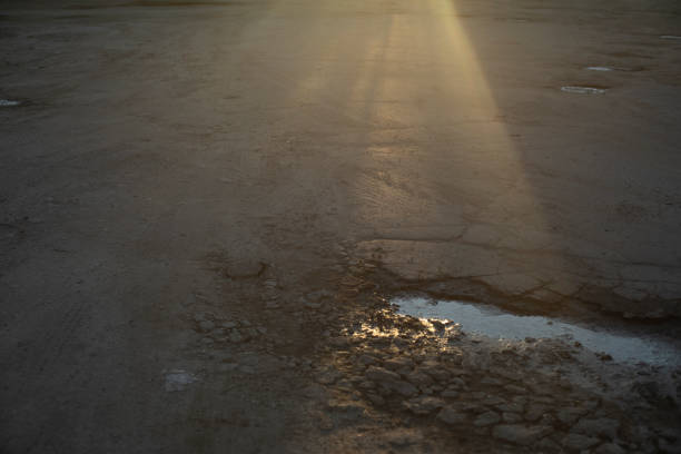 Light on the asphalt. Rays of light on the road. A pit in the asphalt. Pavement.