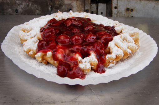 A funnel cake topped with sugar and cherry syrup