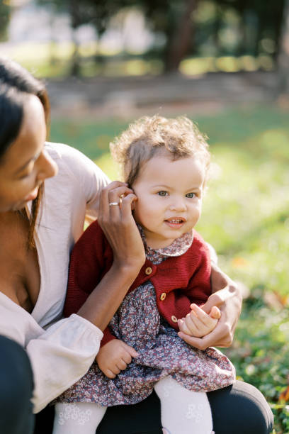 maman lisse les cheveux d’une petite fille assise sur ses genoux dans un parc ensoleillé - 3503 photos et images de collection