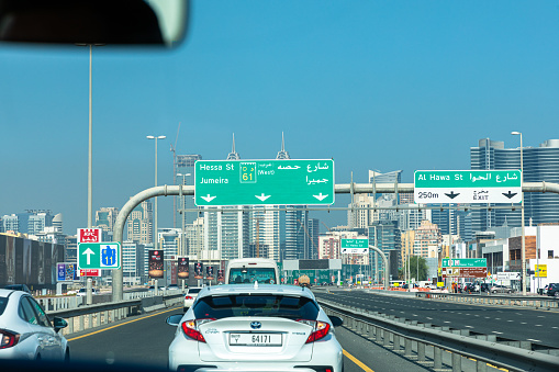 Dubai, United Arab Emirates - October 11, 2023: Road sign in Dubai highway with cars and skyscrapers during a day