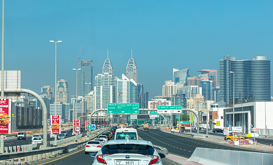 Dubai, United Arab Emirates - October 11, 2023: Road sign in Dubai highway with cars and skyscrapers during a day