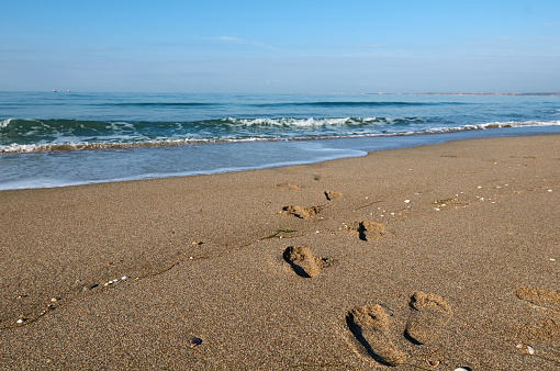 footprints in wet sand beach walk through a sea