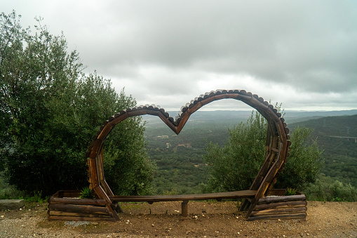 Évoramonte, Alentejo, Portugal. October 29, 2023. Heart-shaped bench in Evoramonte, Alentejo, overlooking vast green fields—an idyllic embrace of nature's love.