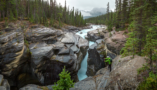 A tourist takes a photo of Mistaya Canyon in Banff National Park, Mistaya River, Alberta, Canada