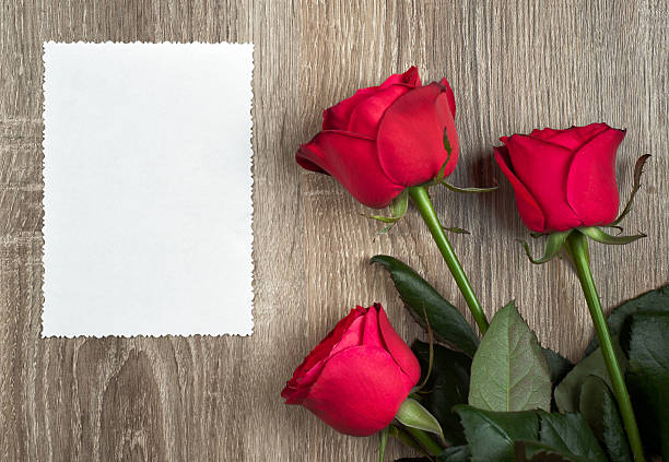 istock three red roses and blank sheet on wood 178414970