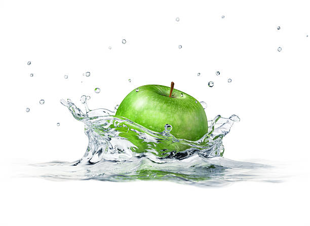 Green apple splashing into water. Close-up side view. stock photo