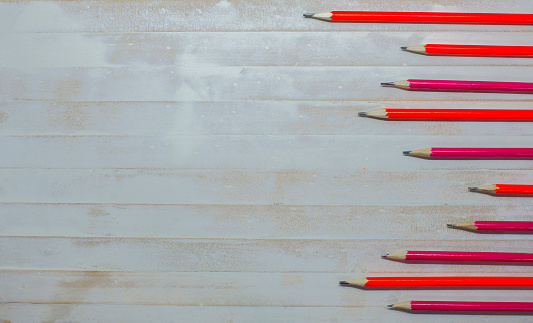 Many red pencils on a white wooden floor background and empty space.