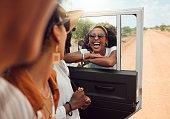Friends, safari and a holiday adventure in nature for black woman in African outdoor game reserve. Diversity, travel and happy road trip, men and women on gravel road sightseeing in bush in Africa.