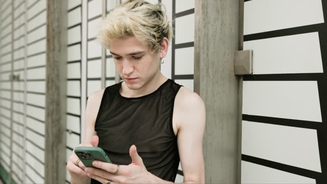 Leisurely gay man using smart phone