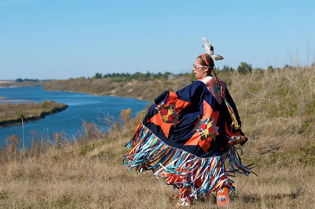 A woman performing a Fancy Shawl Dance along the river in Saskatoon, Saskatchewan