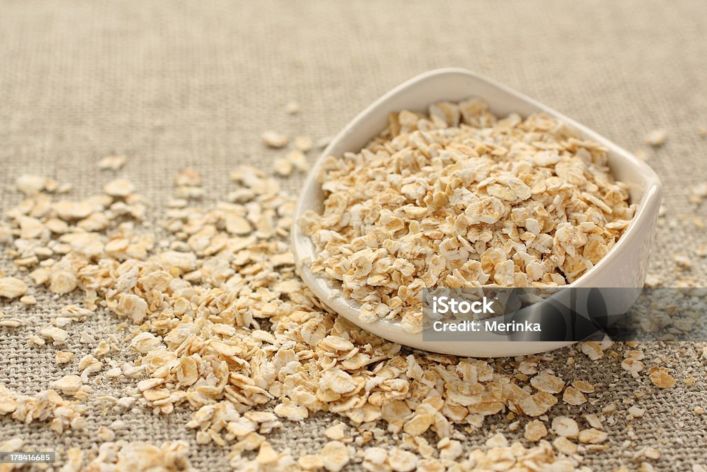 flakes (Copos de avena en blanco sobre fondo sackcloth cerámico bowl - Foto de stock de Agricultura libre de derechos