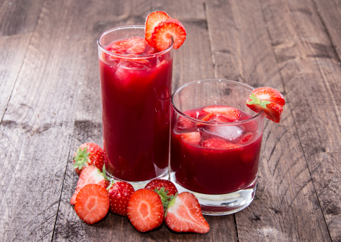 Some glasses with Strawberry Liqueur on wooden background