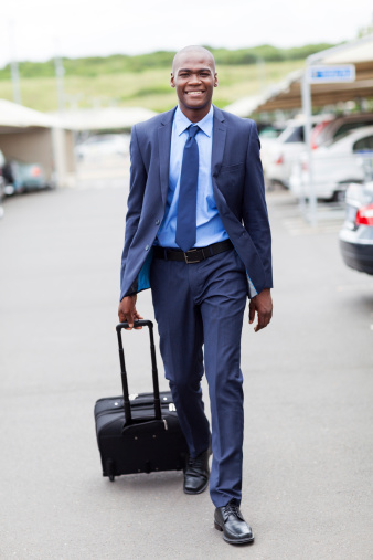 handsome african businessman walking in airport parking lot