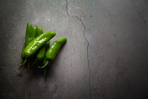 Green chili Serrano pepper (Capsicum annuum), over a marble table. Dark and moody scene.