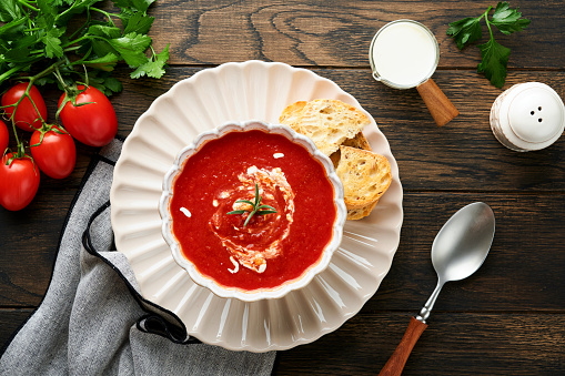 Soup. Tomato cream soup or gazpacho with herbs, seasonings, cherry tomato and parsley in white bowl on dark wooden old background. Healthy vegetable soup. Spanish cold soup. Top view with copy space.