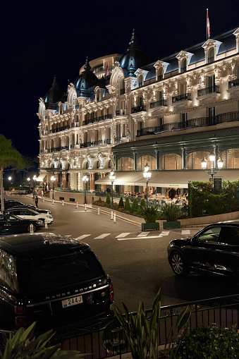 Monaco, Monte-Carlo, 12 November 2022: The famous square of Casino Monte-Carlo is at dusk, attraction night illumination, luxury cars, players, tourists, splashes of fountain