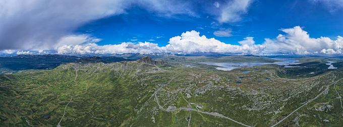 Summer skies and white fluffy clouds above country villages, rolling hills, green fields and the picturesque patchwork pasture of this rural panorama from high above.