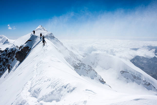 Climbers balancing in blizzard on a narrow mountain ridge Climbers balancing in blizzard on a narrow ridge of Lyskamm (aka Maneater, 4480 m, Alps) mountain climbing photos stock pictures, royalty-free photos & images