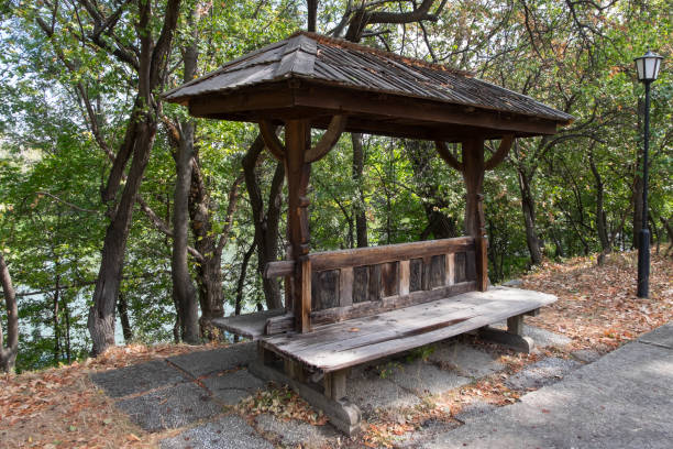 Bucharest, Romania - September 07, 2023: Wooden bench by the lake at the Satului Ethnographic Museum inside Herastrau Park